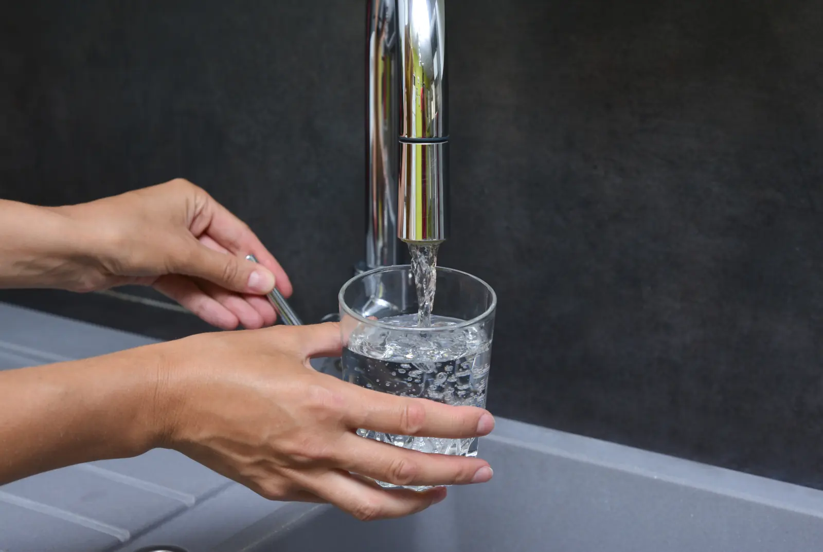 Verre rempli d'eau au robinet d'un évier de cuisine